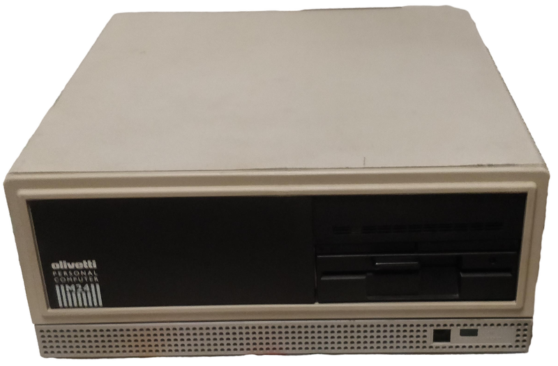 Front shot of the computer with its case on. Beige metallic box with a dark front panel containing on the left the Olivetti brand logo, the "Personal Computer M24 inscription, and on the right two 5.25" rows with a hard drive and a floppy disk drive.